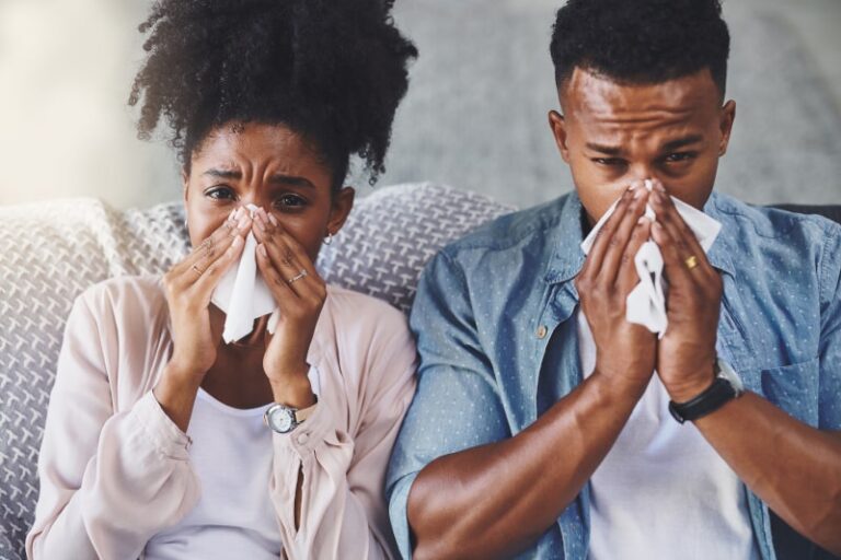Sick Couple Blowing Noses on Couch